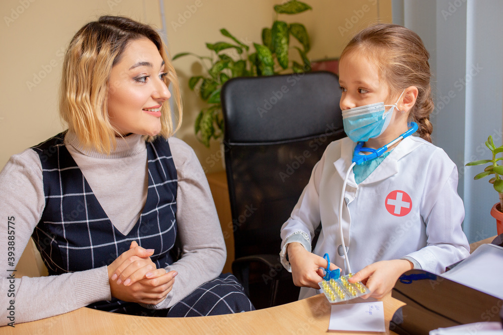 Little girl playing pretends like paediatrician doctor examining a patient in comfortabe medical office. Healthcare, childhood, medicine, education concept. Having fun while giving pills for patient