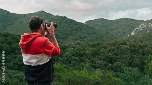 Back half body view of a photographer taking pictures on the mountains of Sardinia