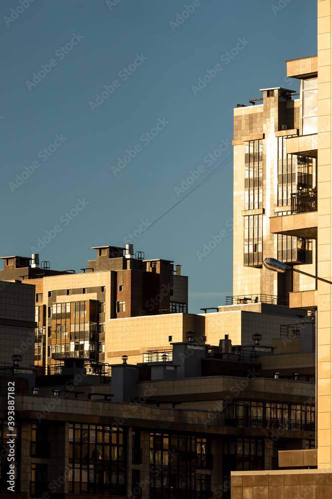 Modern architecture in evening sunset light. Glass facades and windows enlightened by warm yellow sun.