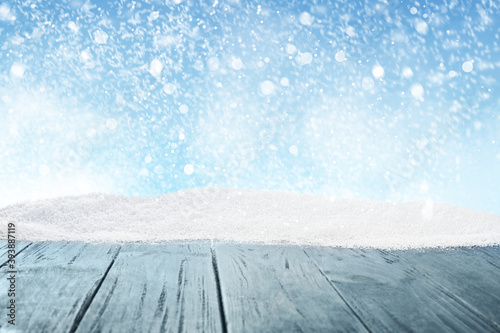 Wooden surface with snow against blue background, bokeh effect © New Africa