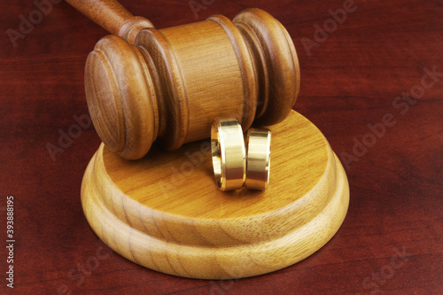 Two wedding rings and wooden judge gavel. Family law, divorce and marriage concept.