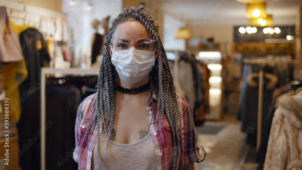 Young woman with dreadlocks wearing coronavirus safety mask at retail shop