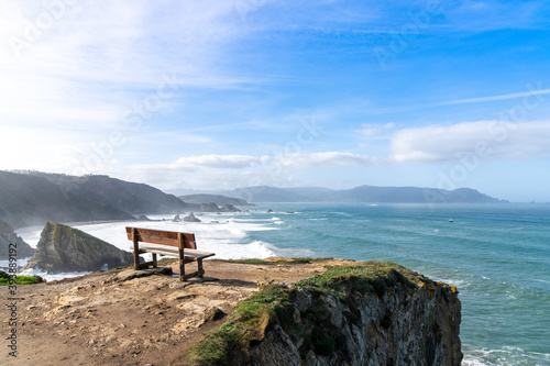 scenic viewpoint with wooden bench on beautiful ocean coast with high cliffs and big waves photo