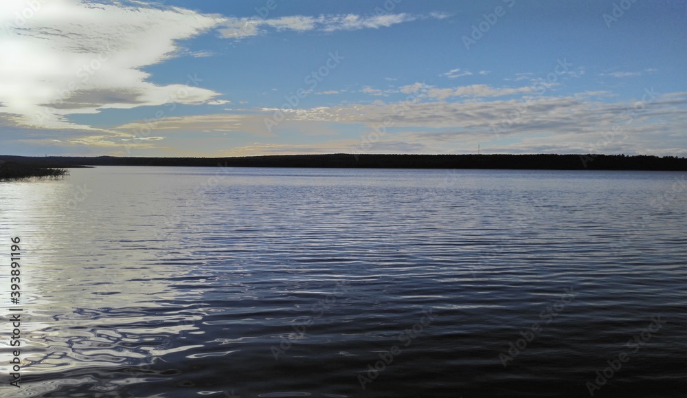 Flood of the Vuoksa river under the blue sky.
Leningrad region. Summer day. Vuoksa river. The calm waters of the river flow under the clouds against the bright sky. Light ripples on the water. a dark 