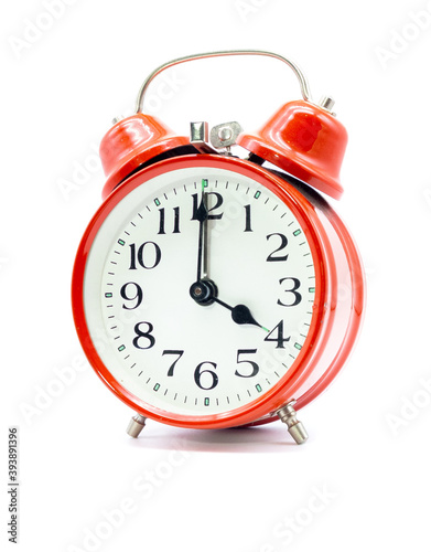 Roter Wecker zeigt vier Uhr vor weißem Hintergrund