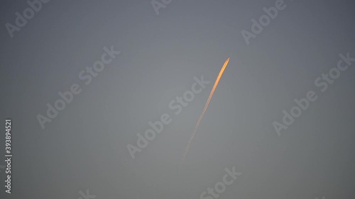 Airplane flying in the sky and its contrail at sunset, footage has been sped up two times