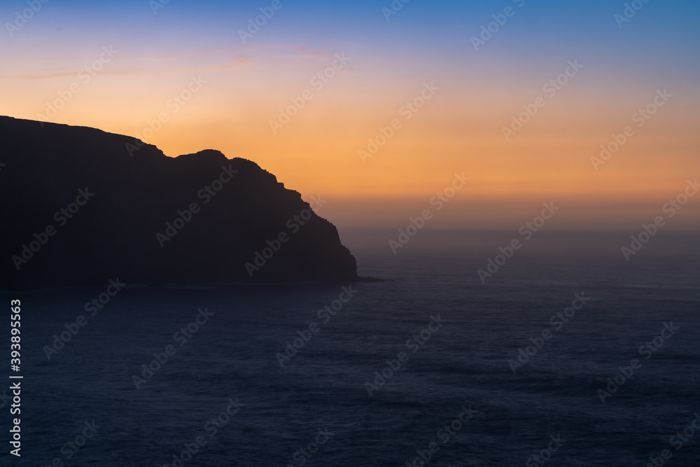 sunrise over the ocean with cliff in silhouette and beautiful colors