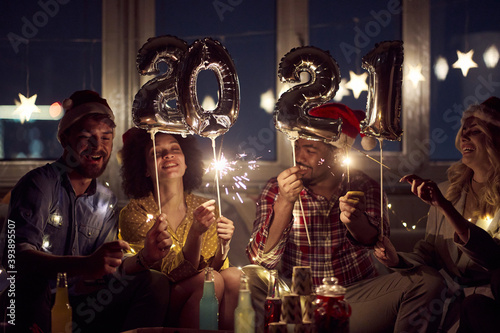 Cheerful couples enjoying drinks and sprinklers at New Year eve home party. New Year, home party, friends time together