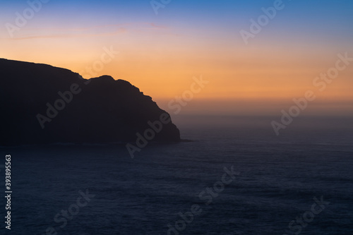 sunrise over the ocean with cliff in silhouette and beautiful colors © makasana photo