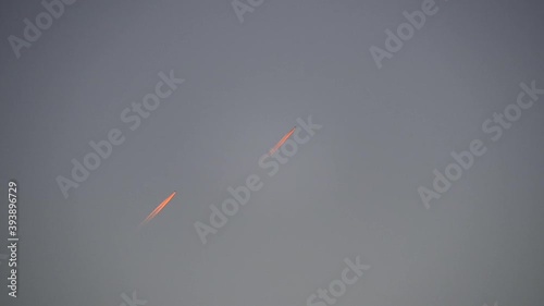 Two airplanes following the same route and their contrails at sunset