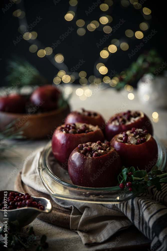 Preparing Christmas baked apples stuffed with nuts, lingonberry and cinnamon. Glass baking form with apples on festive decorated table..