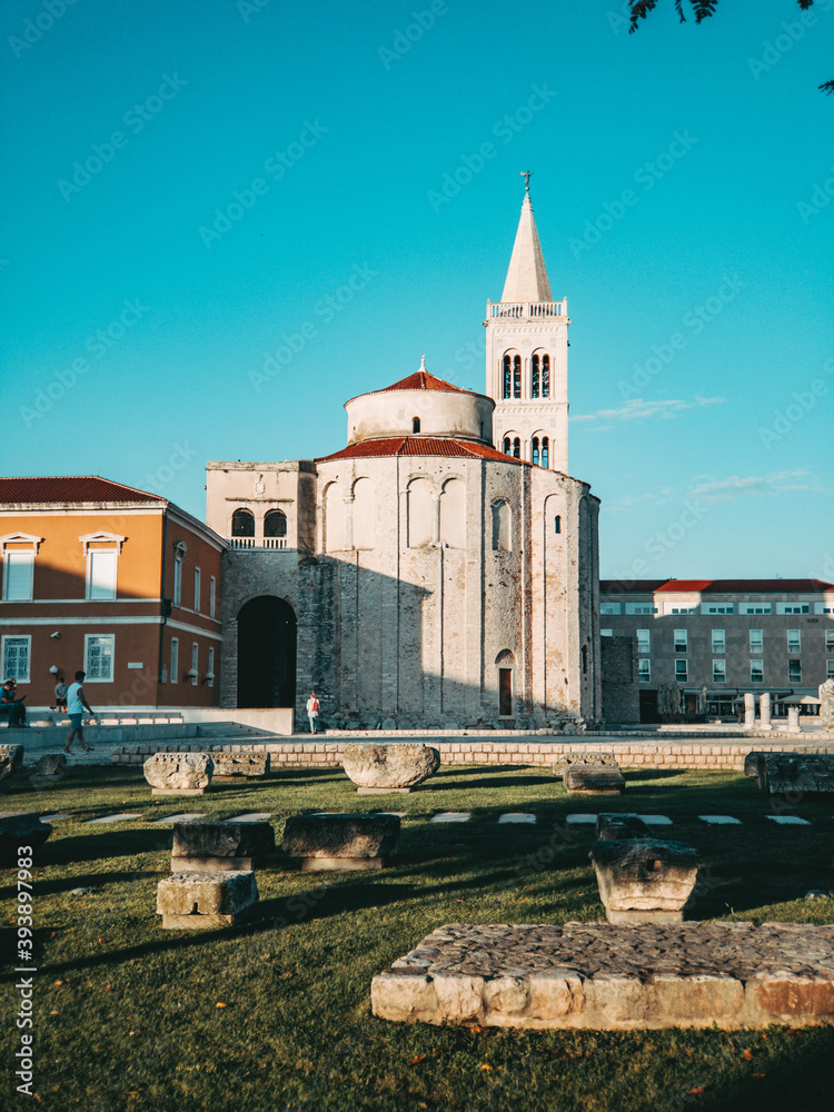 Fototapeta premium a view of the church of saint donatus during sunny day and old ruins architecture in the foreground summer in croatia