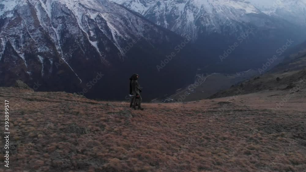 Aerial view of a man and a woman walking high in the mountains and admiring the view. Mountain sports trekking Aerial view of a man and a woman walking high in the mountains and admiring the view. Mountain sports trekking