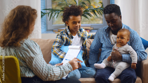 Social worker consulting smiling young single father with kids at home.