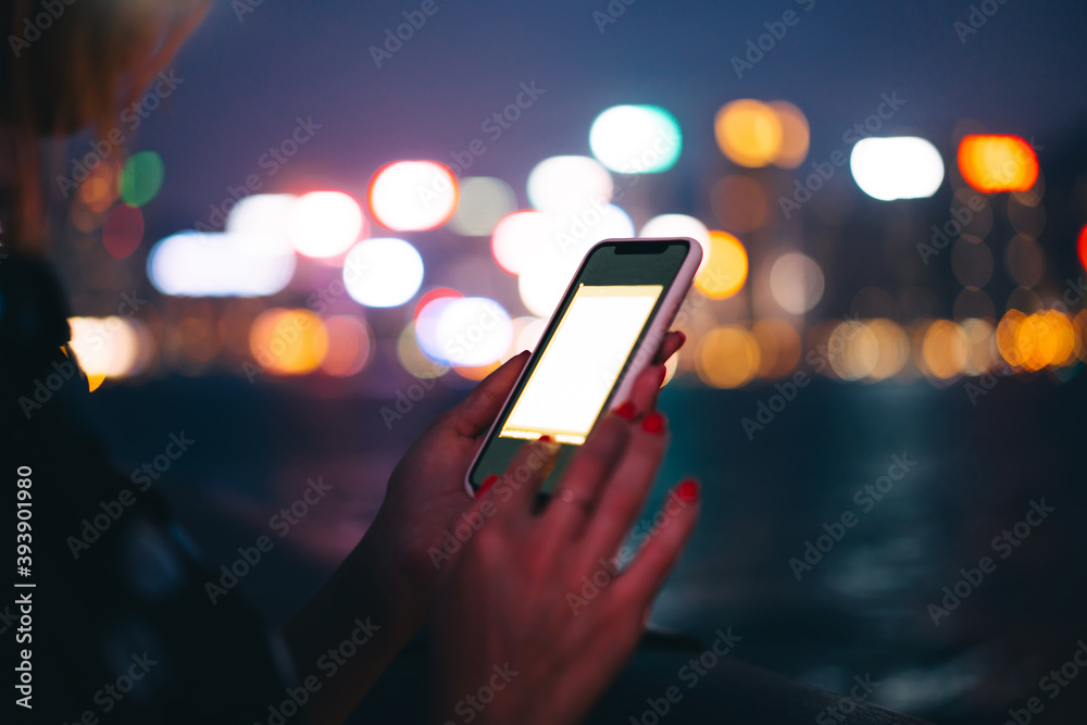 Young woman using smartphone with copy space screen on blurred night city background Young woman using smartphone with copy space screen on blurred night city background