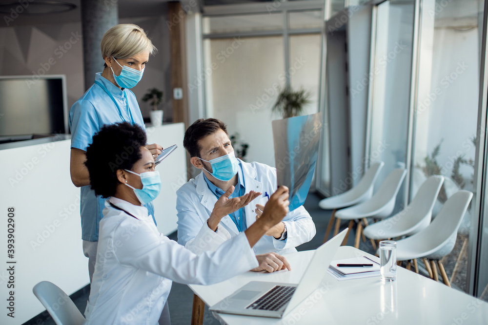Group of doctors cooperating while examining X-ray of a patient at the hopital. Group of doctors cooperating while examining X-ray of a patient at the hopital.