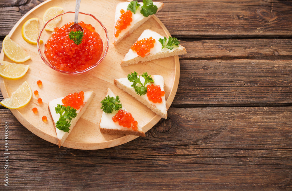 toast with red caviar on  wooden tray