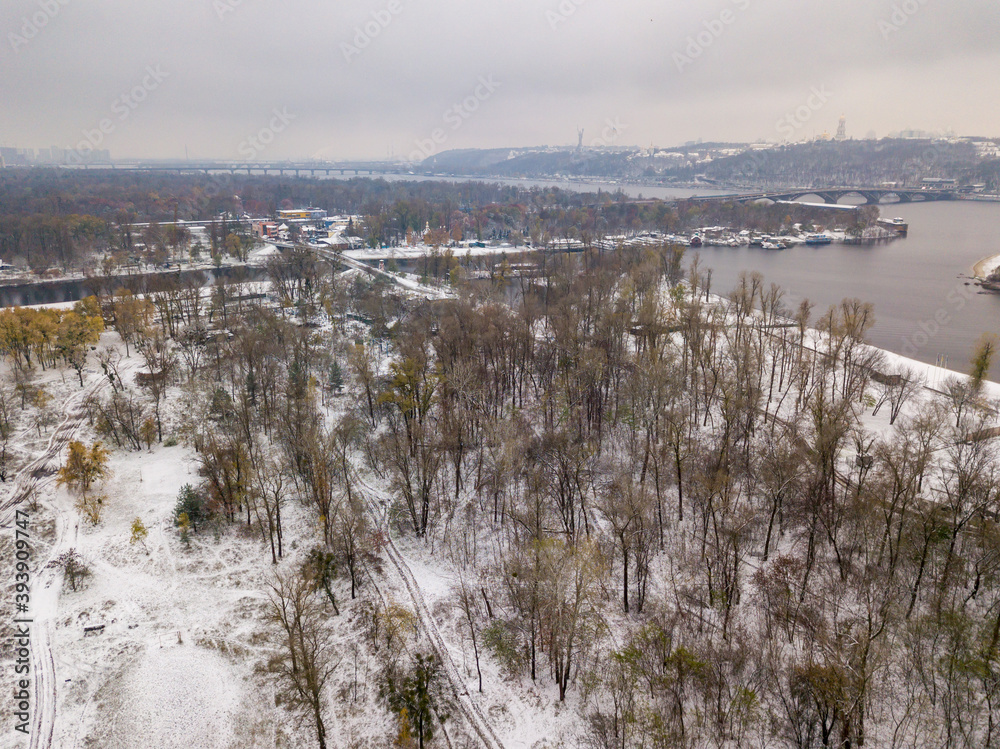 Aerial drone view. Snow-covered trees in the park. A thin layer of the first snow on earth.