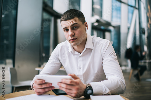 Serious young businessman using tablet in modern cafe