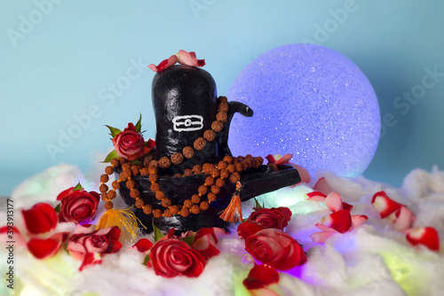 Black Shivalingam figure in Divali lights with rudraksha beads and roses. photo