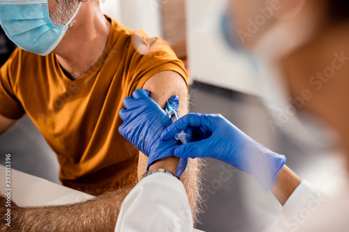 Close-up of senior man receiving vaccine during coronavirus pandemic.