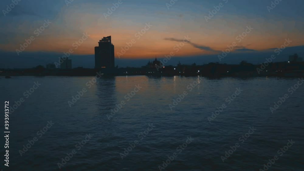Time lapse of twilight sunset river scenery silhouette building and boats rides on the river Time lapse of twilight sunset river scenery silhouette building and boats rides on the river