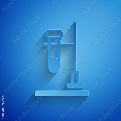 Paper cut Glass test tube flask on fire heater experiment icon isolated on blue background. Laboratory equipment. Paper art style. Vector.