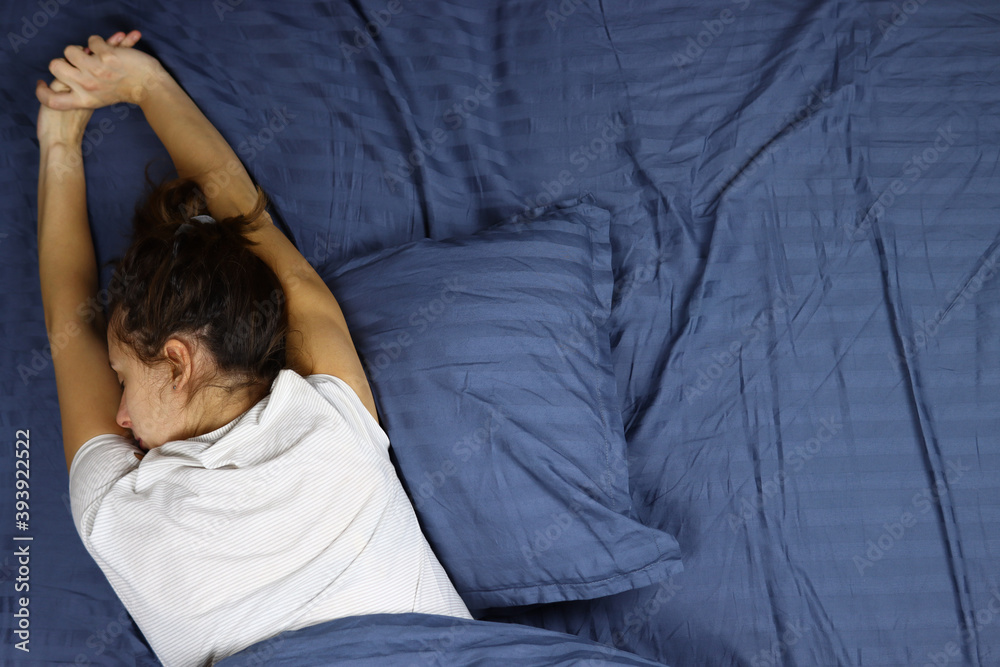 Young woman wakes up, stretches in bed Young woman wakes up, stretches in bed