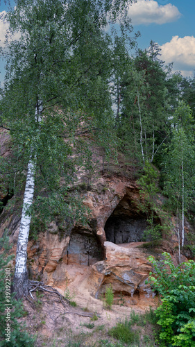 Sandstone Caves in Ligatne, Latvia. View to Cave Rock Lustuzis (Lustūzis) on the Bank of Ligatne River. Caves With Old Wooden Doors. photo