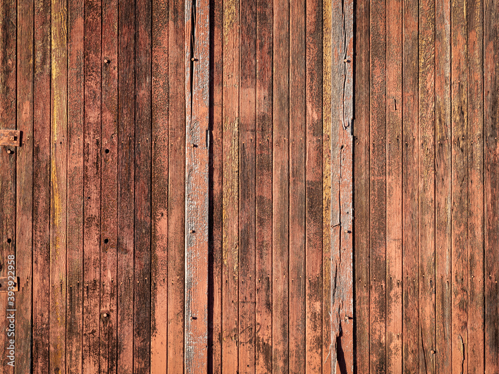 rustic wooden background of a barn wall - planks of weathered pine red painted wood with  knots, holes and nails