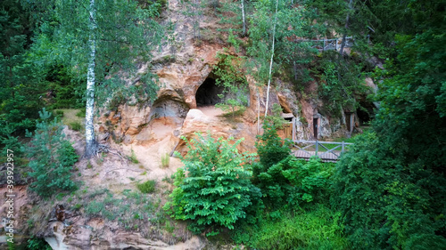 Sandstone Caves in Ligatne, Latvia. View to Cave Rock Lustuzis (Lustūzis) on the Bank of Ligatne River. Caves With Old Wooden Doors.