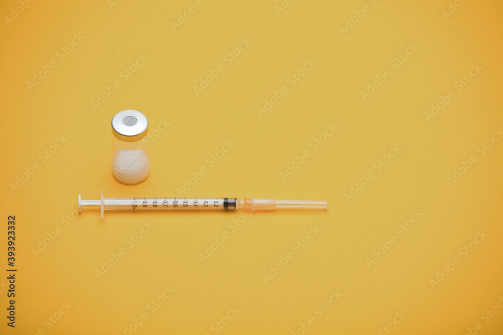 syringe with vaccine bottle, yellow background syringe with vaccine bottle, yellow background