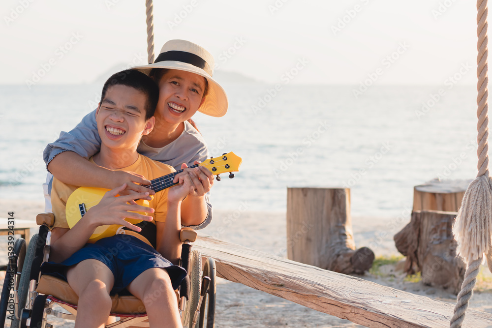 Asian special child on wheelchair is singing, playing ukulele happily ...