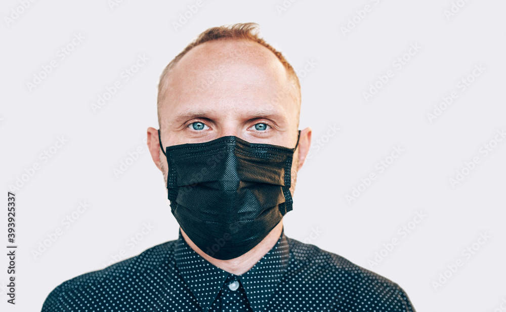Portrait of man using a black facial mask during a COVID-19 world pandemic looking at camera. Self-protection and stop virus spreading measures concept image Portrait of man using a black facial mask during a COVID-19 world pandemic looking at camera. Self-protection and stop virus spreading measures concept image