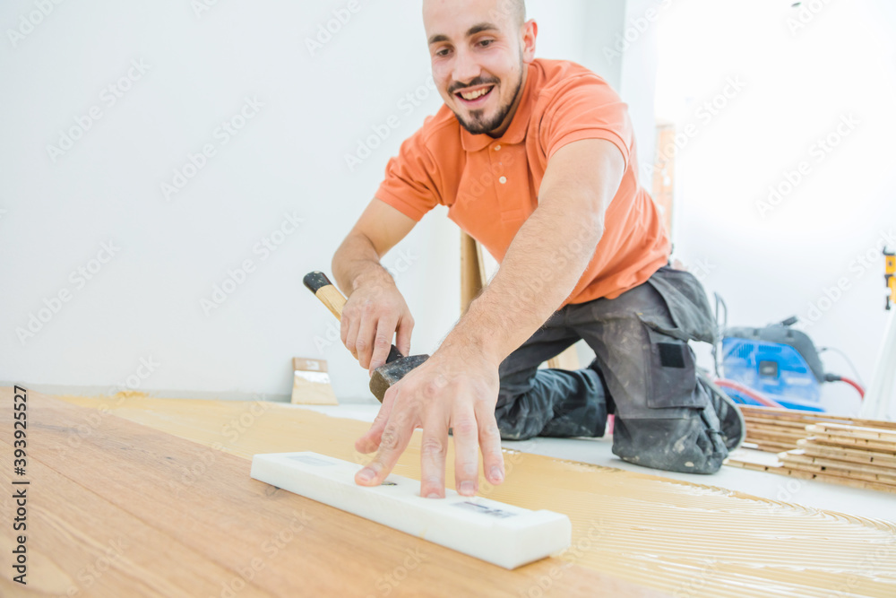 A Male Worker install wood floor on a house A Male Worker install wood floor on a house