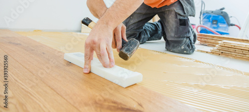 A Male Worker install wood floor on a house