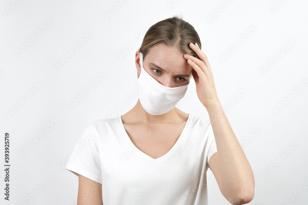 Young blond woman in virus disposable face mask keeping raised hand on her head expressing feelings, sadness, worried. Protection for covid-19 Young blond woman in virus disposable face mask keeping raised hand on her head expressing feelings, sadness, worried. Protection for covid-19