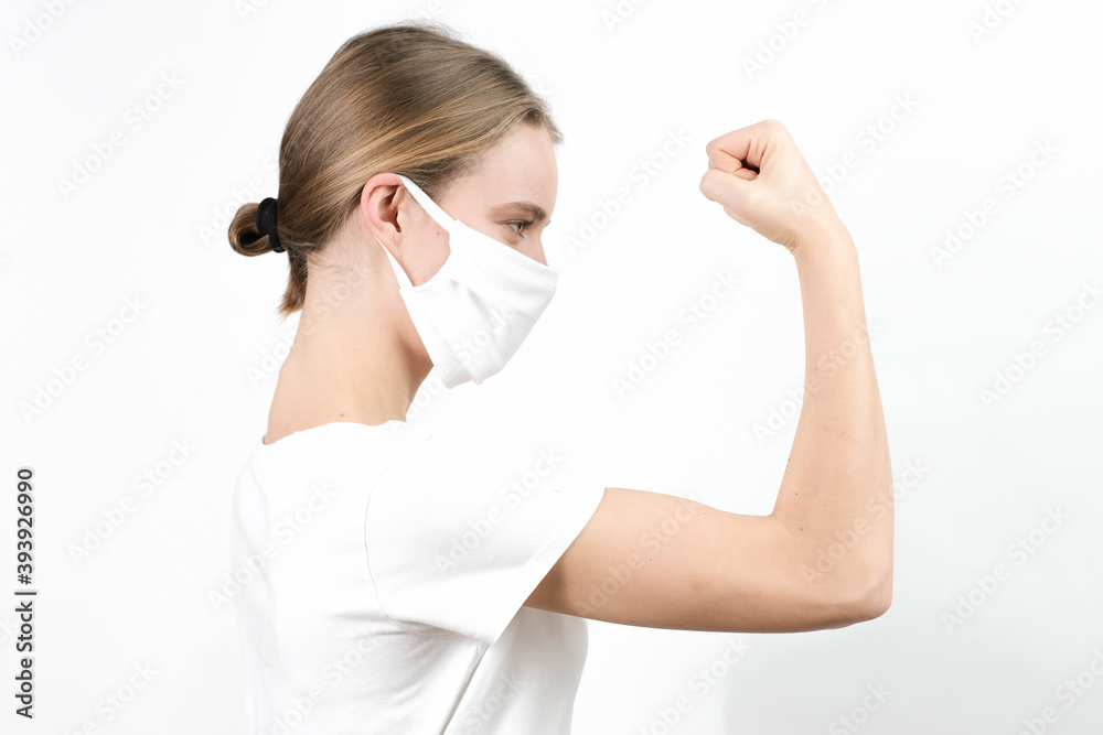 Young, strong, independent woman in disposable mask showing her muscles and strength. Young, strong, independent woman in disposable mask showing her muscles and strength.