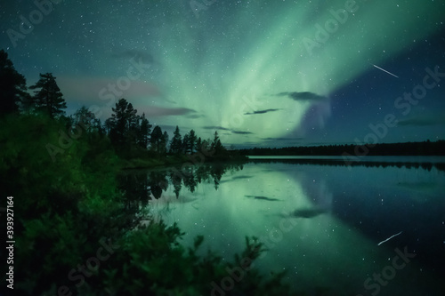 Shooting star and auroras reflecting from a still lake