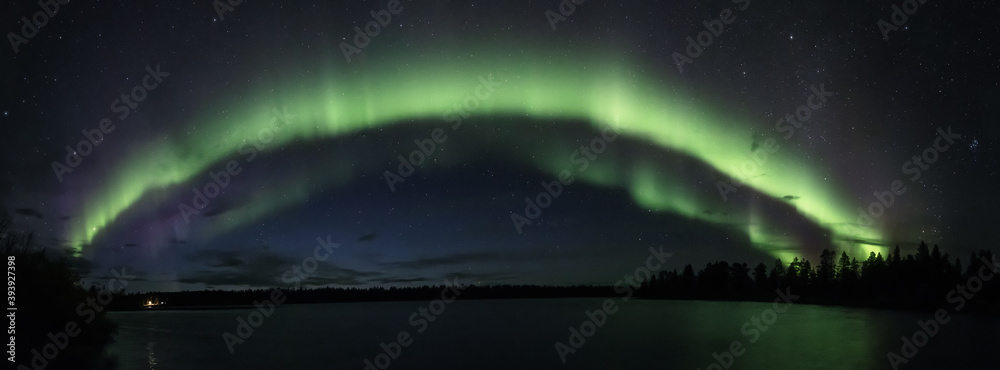 Aurora arc panorama above a still lake