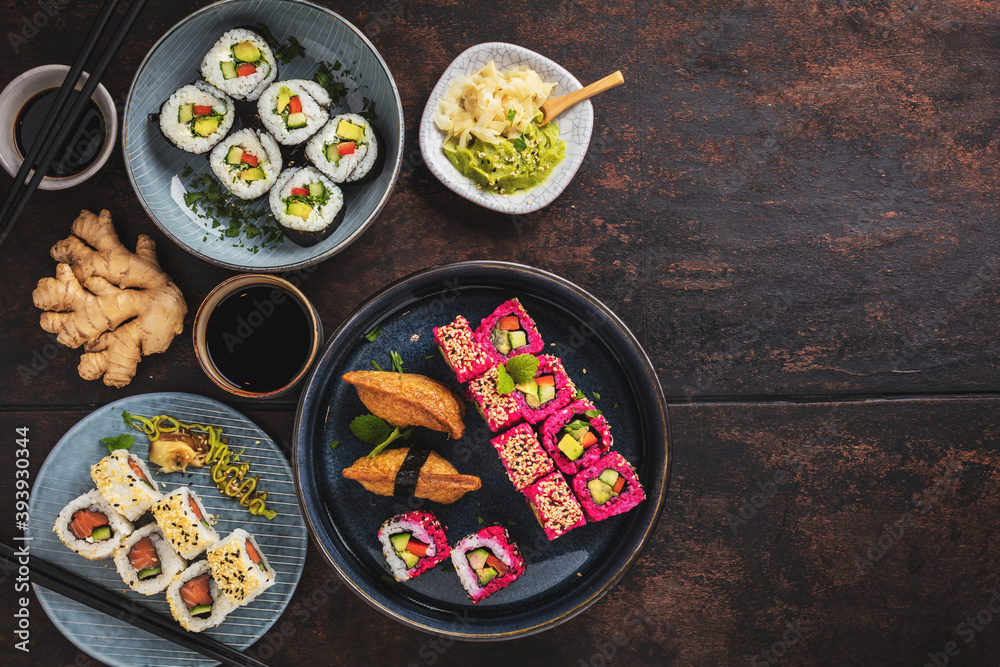 Delicious rolls, sushi and maki on a dark wooden Board with chopsticks. On black rustic background Delicious rolls, sushi and maki on a dark wooden Board with chopsticks. On black rustic background