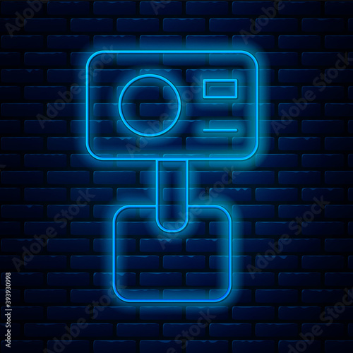 Glowing neon line Action extreme camera icon isolated on brick wall background. Video camera equipment for filming extreme sports. Vector.