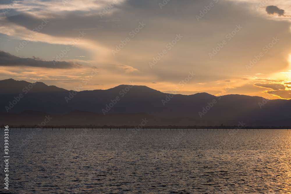 A Silhouette Fisherman row boat in Phayao Lake. Scenery sunset in Phayao Province , Thailand. A Silhouette Fisherman row boat in Phayao Lake. Scenery sunset in Phayao Province , Thailand.