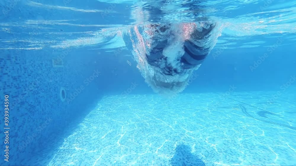 Fit athletic man dives head jump into the refreshing swimming pool, slow motion
