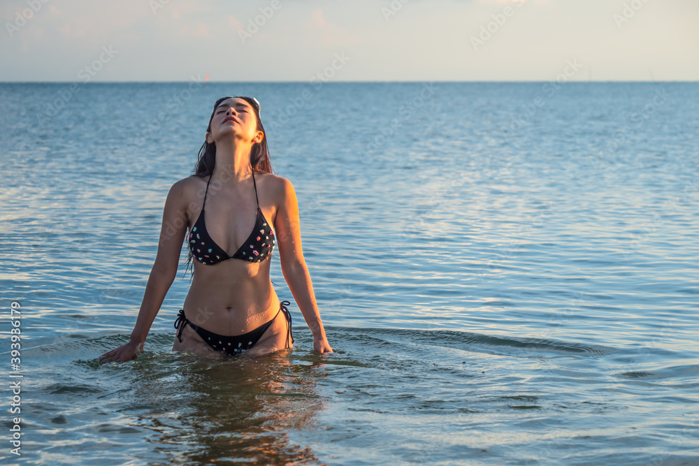 Sexy girls in bikini wear water on the beach, Young woman standing in the water at the sea