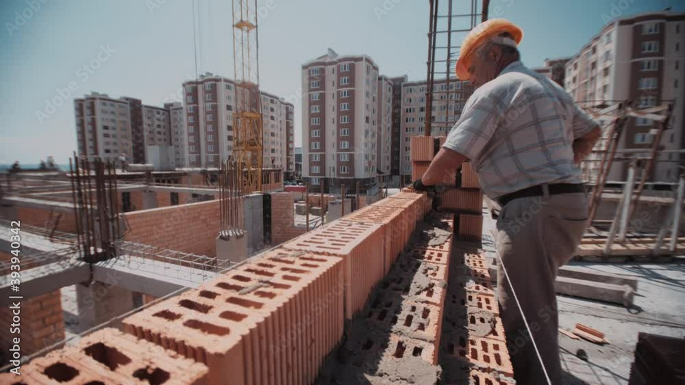 Close up trough the wall to a builder who place a bricks. Dynamic footage from a building site. Close up trough the wall to a builder who place a bricks. Dynamic footage from a building site.