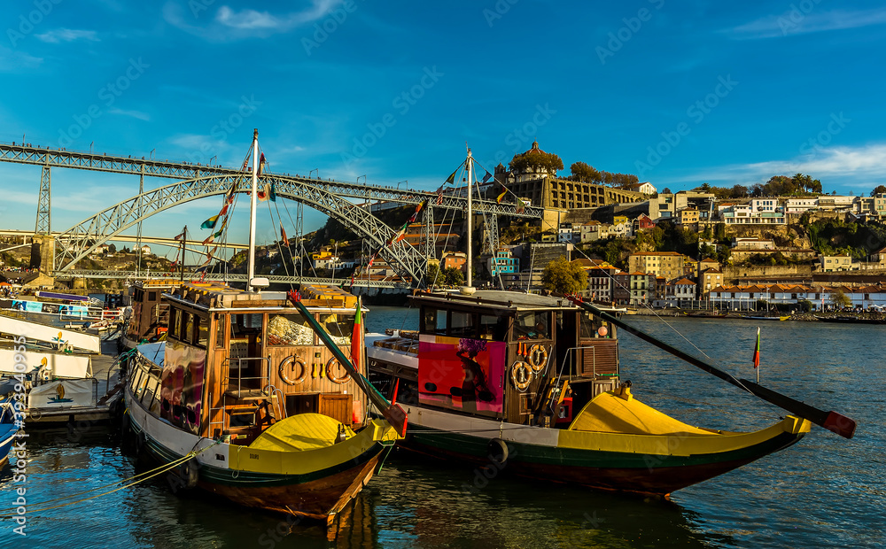 Tourist boats moored up on the Douro river by the Dom Luiz bridge in Porto, Portugal on a  sunny afternoon