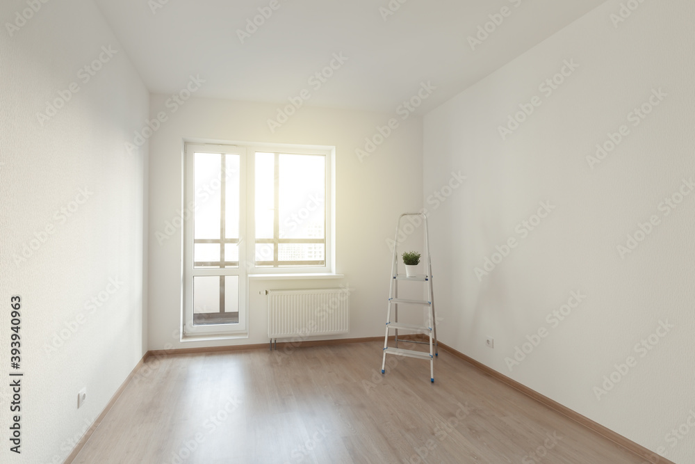Empty room with white wall interior, ladder and window view.
