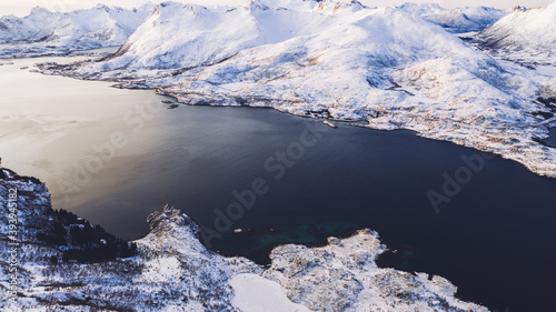 Breathtaking bird's eye view of fjord mountains covered with snow in winter. Aerial top view of scenery rock peaks, picturesque beautiful nature landscape. Lofoten Island surrounds by Nordic sea.