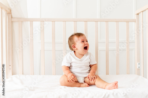 Photo baby boy six months old crying in his crib